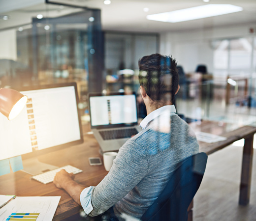 A man working at his computer in the office on a desk
